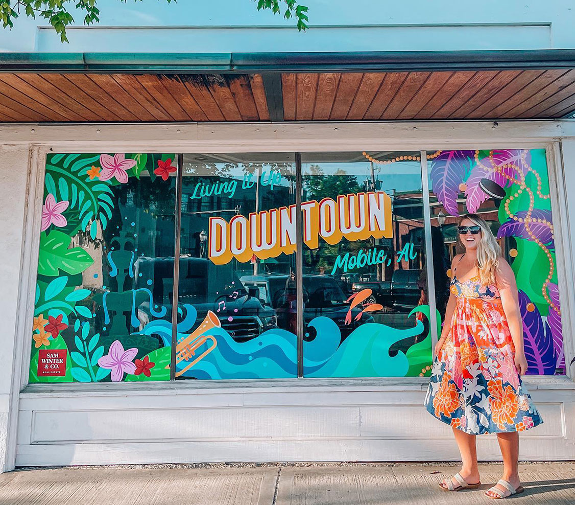 window painting in downtown mobile with young lady smiling in sundress