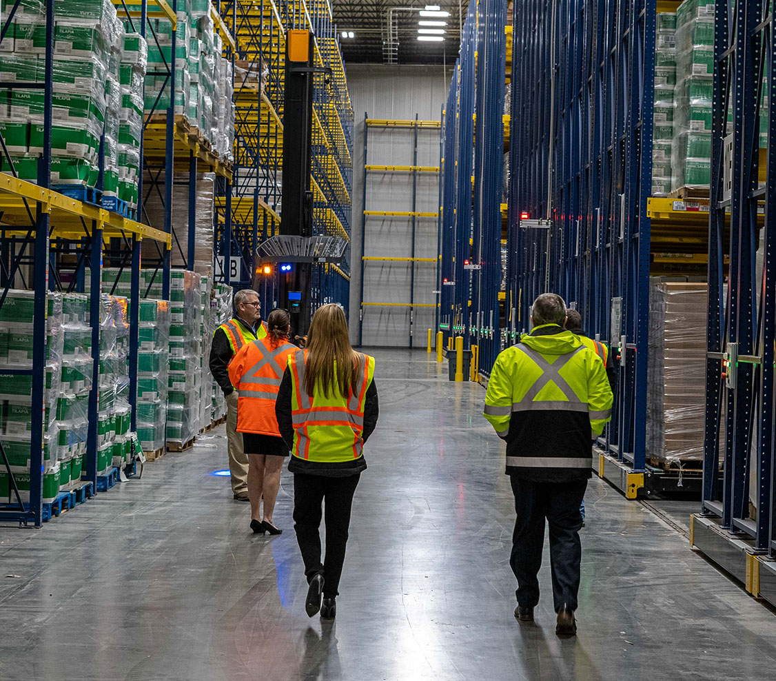 people in high visibility vests walking through warehouse