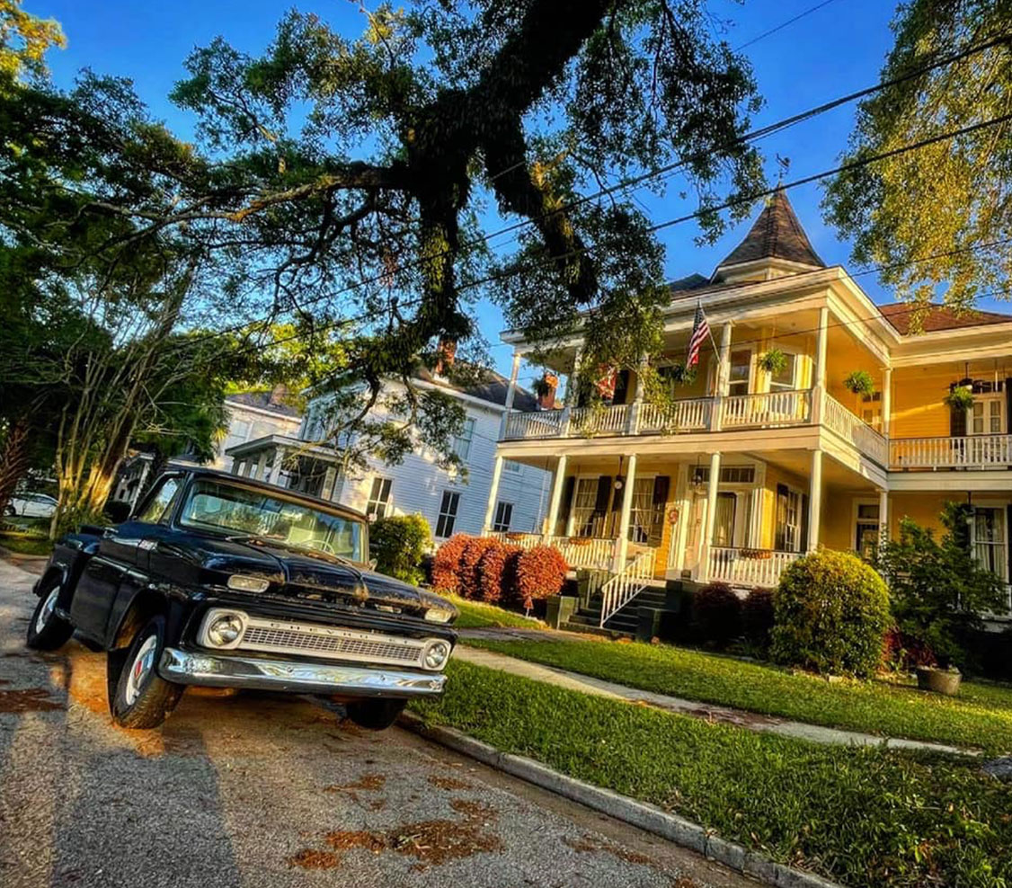 two story home with vintage step side chevy truck out front. Black paint with nice patina.