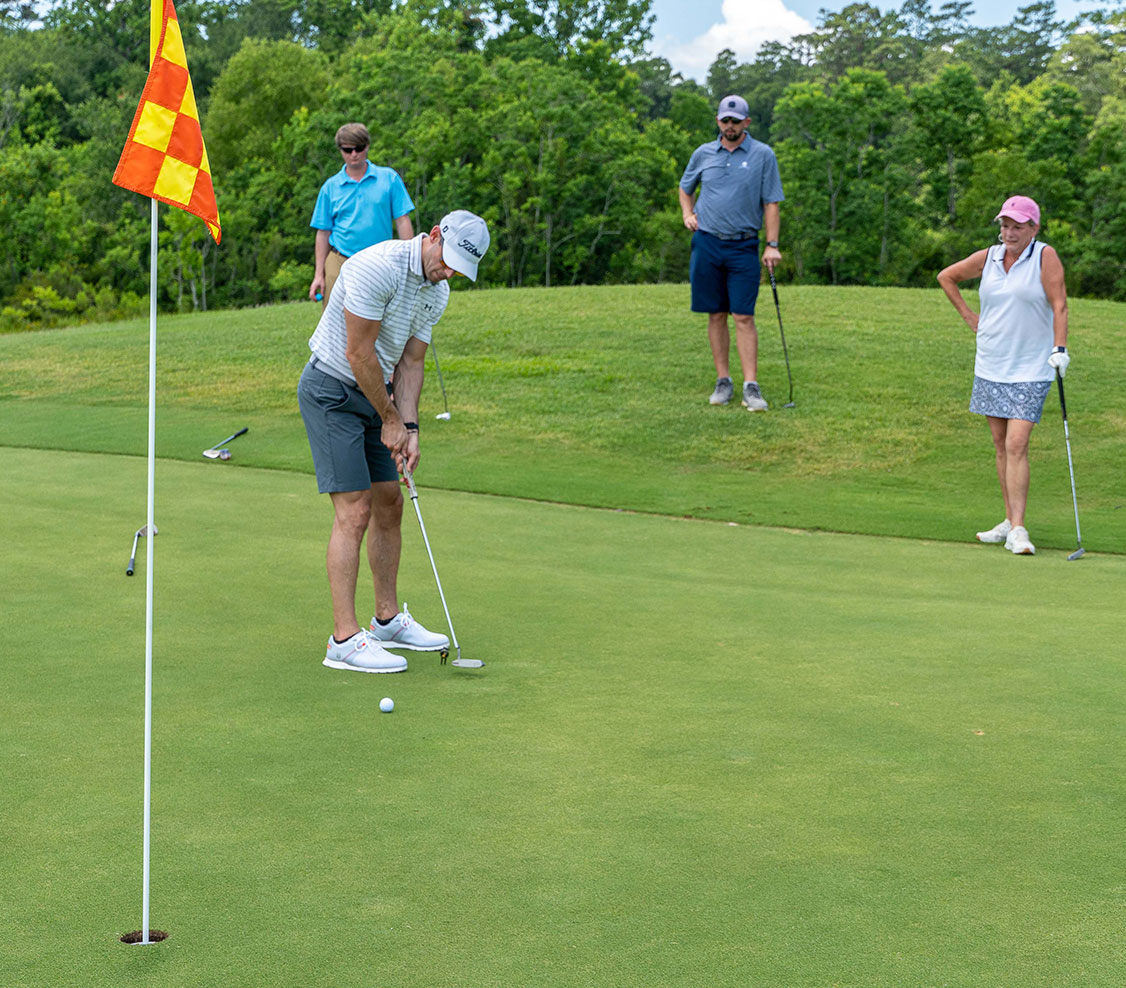 Four people putting on golf course
